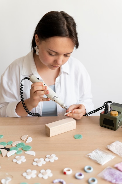 Vrouwelijke ambachtsman aan het werk in het atelier met lijmpistool