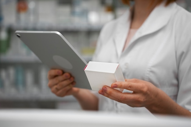 Gratis foto vrouwelijke apotheker die met tablet in de apotheek werkt