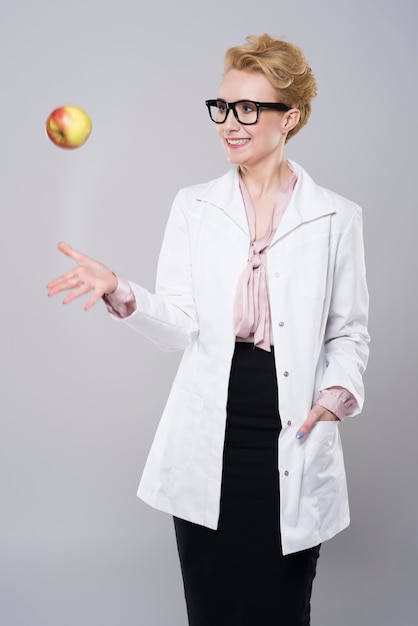 Gratis foto vrouwelijke arts die een appel werpt