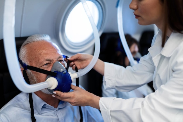 Vrouwelijke arts die het zuurstofmasker van een oudere patiënt in een hyperbare kamer in de kliniek aanpast Focus is een senior man