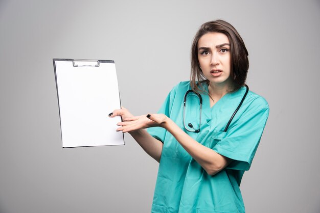 Vrouwelijke arts die klembord toont en over resultaten vraagt. Hoge kwaliteit foto