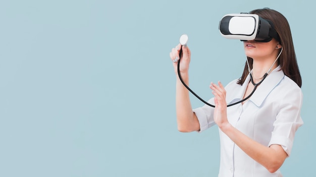 Vrouwelijke arts die stethoscoop en virtuele werkelijkheidshoofdtelefoon met exemplaarruimte gebruiken