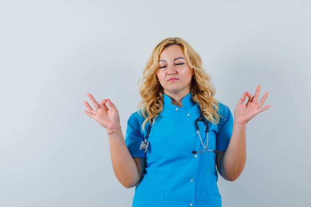Vrouwelijke arts in blauw uniform mediteren en gericht kijken