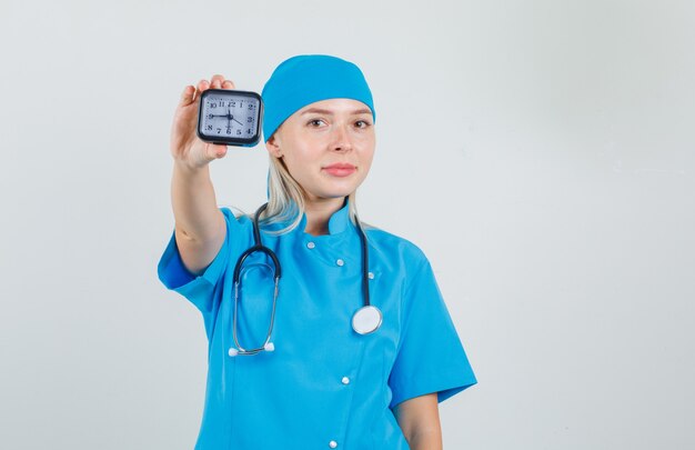 Vrouwelijke arts in blauw uniform met klok en glimlachen