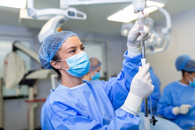 Vrouwelijke arts in de operatiekamer die medicijnen door een IV-operatieconcept brengt