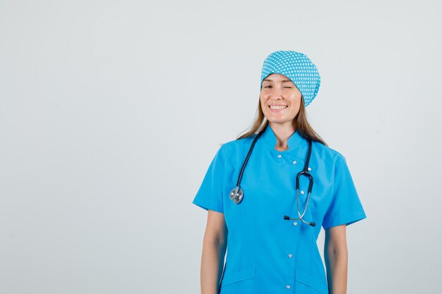 Vrouwelijke arts knipperend oog en lachend in blauw uniform