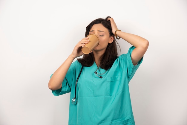 Vrouwelijke arts kopje koffie drinken op witte achtergrond. hoge kwaliteit foto