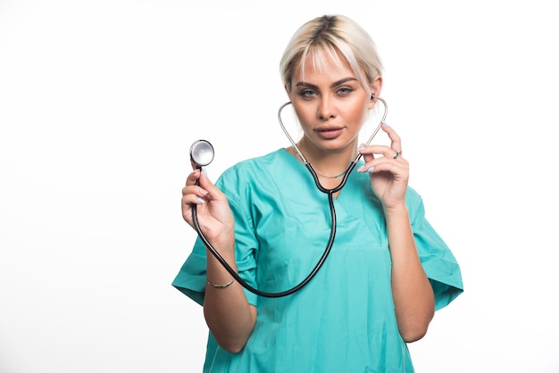 Vrouwelijke arts met behulp van een stethoscoop op een witte muur.