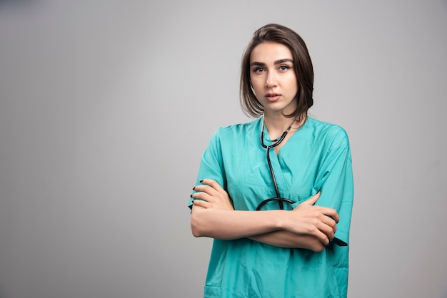 Vrouwelijke arts met een stethoscoop die zich op grijze achtergrond bevindt. Hoge kwaliteit foto