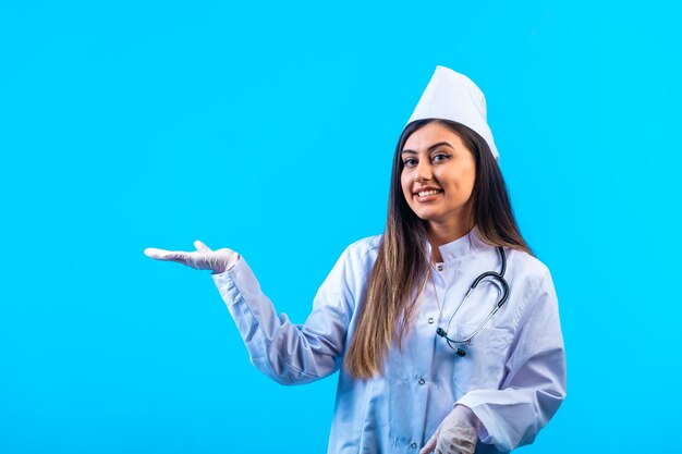 Vrouwelijke arts met een stethoscoop iets introduceren en glimlachen