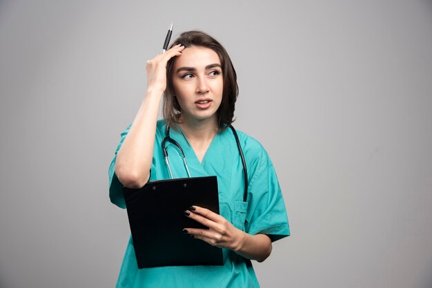 Vrouwelijke arts met hoofdpijn op een grijze achtergrond. Hoge kwaliteit foto