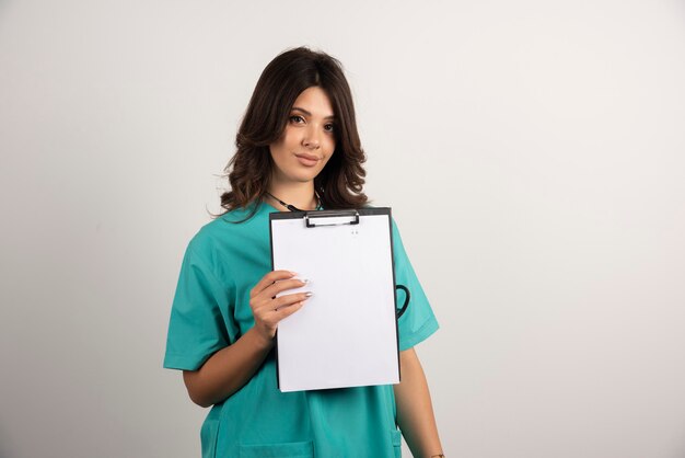 Vrouwelijke arts poseren met klembord op wit