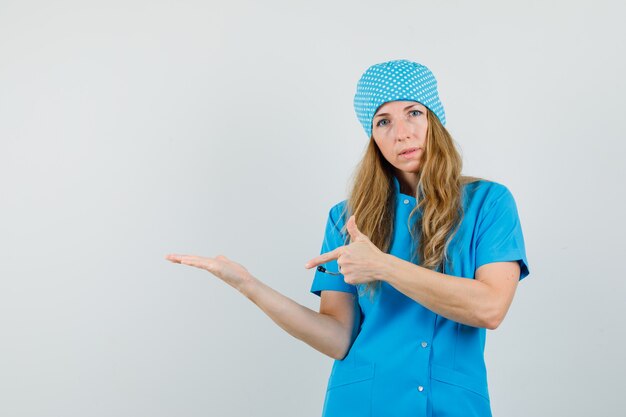 Vrouwelijke arts wijzend op handpalm uitgespreid in blauw uniform