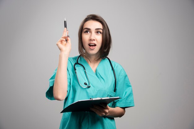 Vrouwelijke arts wijzend op iets op een grijze achtergrond. Hoge kwaliteit foto