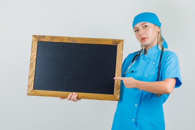 Vrouwelijke arts wijzende vinger op bord in blauw uniform