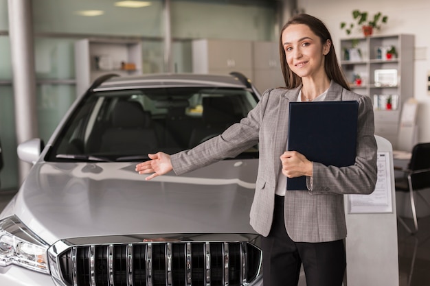 Vrouwelijke autohandelaar die een auto toont