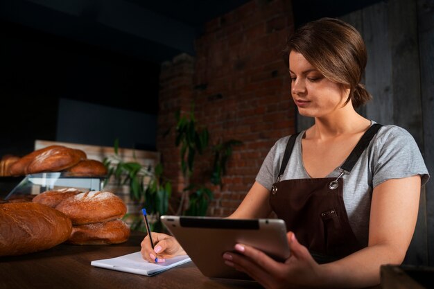 Vrouwelijke bakker in de winkel met tablet die online bestellingen aanneemt