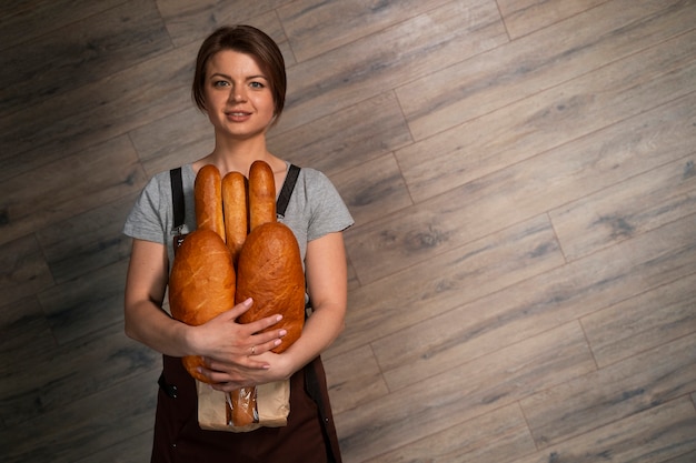 Gratis foto vrouwelijke bakker poseren met gebakken brood