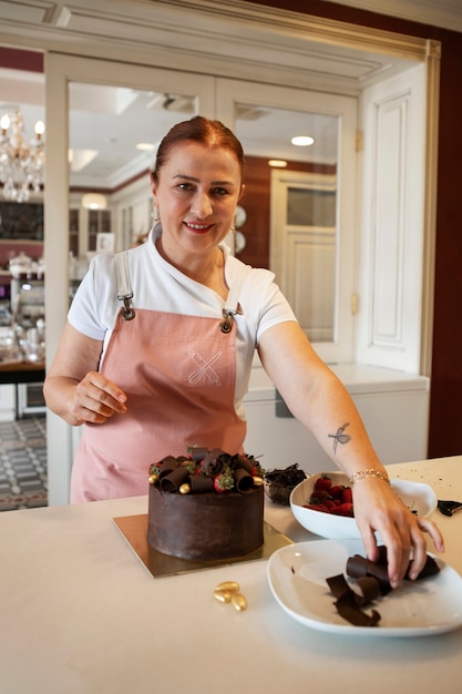 Gratis foto vrouwelijke banketbakker met chocoladetaart in de patisserie