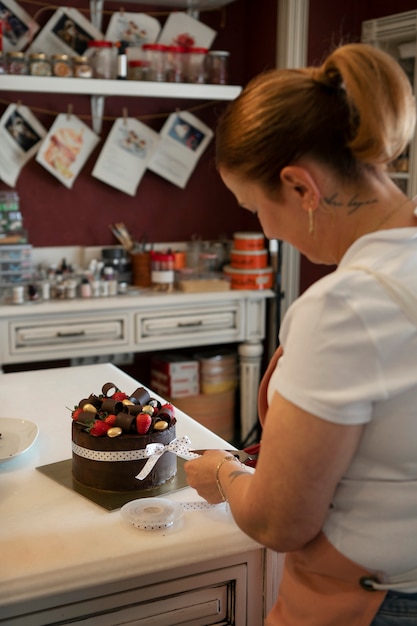 Vrouwelijke banketbakker met chocoladetaart in de patisserie