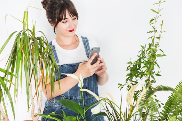 Vrouwelijke bloemist die cellphone gebruiken dichtbij installaties