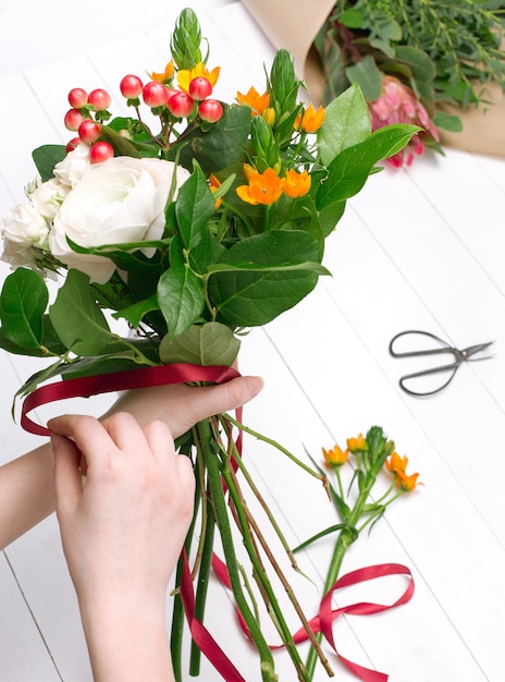 Gratis foto vrouwelijke bloemist die mooi boeket maakt bij bloemenwinkel