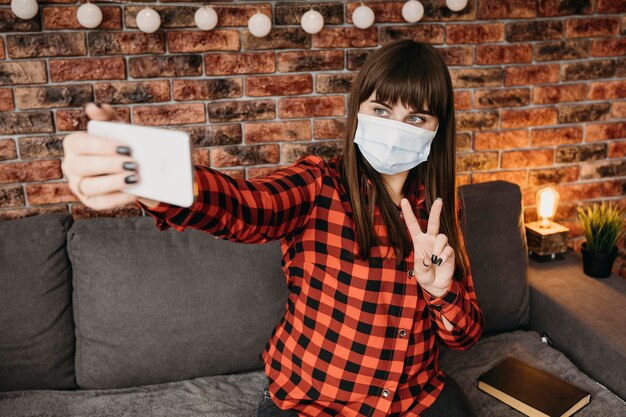 Vrouwelijke blogger met medisch masker online streaming met smartphone