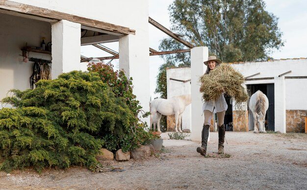 Vrouwelijke boer met hooi voor haar paarden