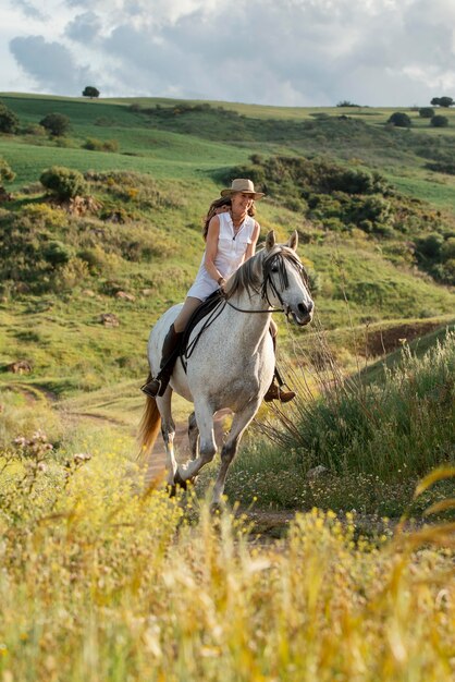 Vrouwelijke boer paardrijden buiten in de natuur