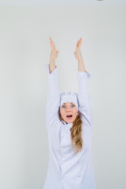 Vrouwelijke chef-kok armen in wit uniform strekken en vreugdevol kijken