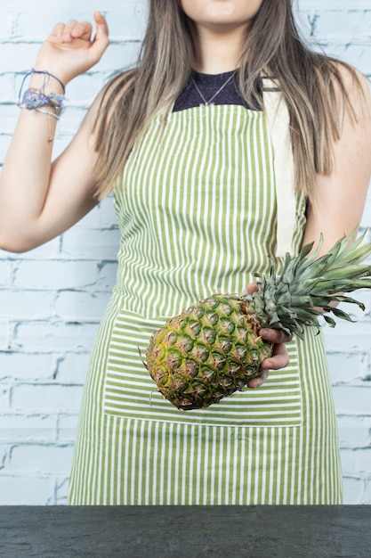 Vrouwelijke chef-kok die een ananas in handen houdt