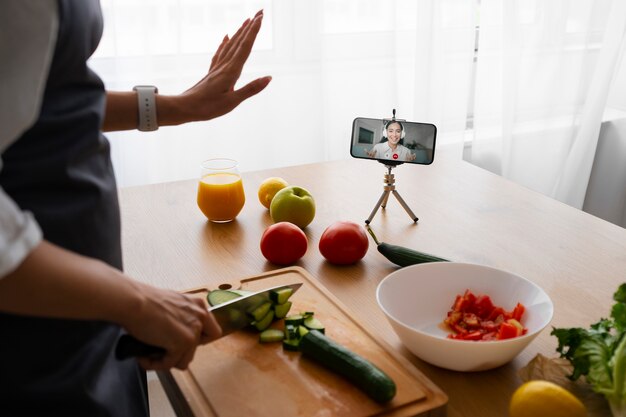 Vrouwelijke chef-kok die een videogesprek voert tijdens het koken