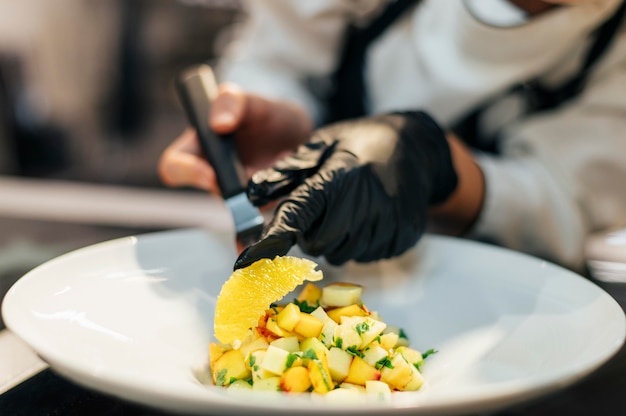 Vrouwelijke chef-kok die oranje plak op schotel plaatst