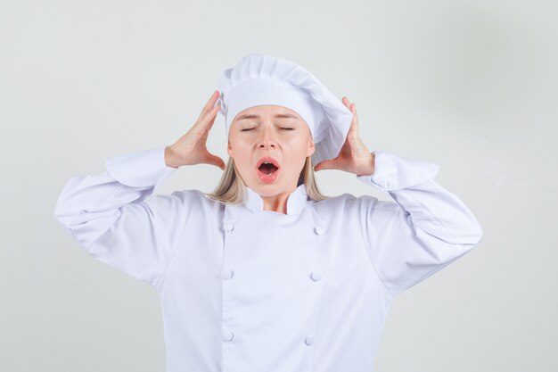 Vrouwelijke chef-kok hand in hand in de buurt van hoofd in wit uniform en op zoek geïrriteerd.