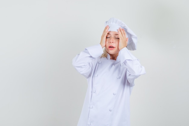 Vrouwelijke chef-kok hand in hand om in wit uniform te gaan en sorry te kijken.