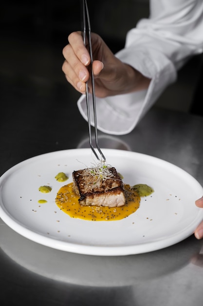 Vrouwelijke chef-kok in de keuken die een bord biefstuk bereidt