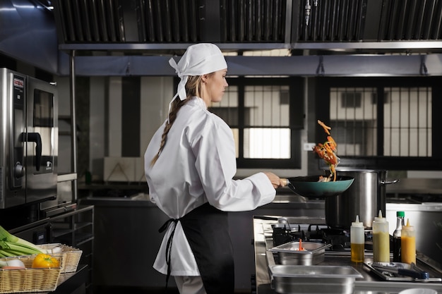 Vrouwelijke chef-kok in de keuken die voedsel frituurt