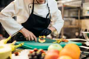 Gratis foto vrouwelijke chef-kok met handschoen hakkende perzik