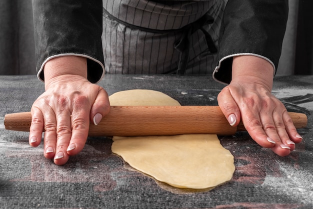 Gratis foto vrouwelijke chef-kok rollend deeg