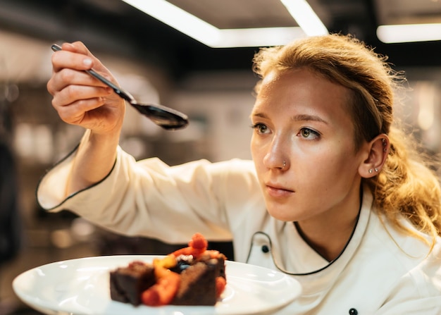 Vrouwelijke chef-kok saus over schotel zetten