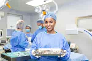 Gratis foto vrouwelijke chirurg in chirurgisch uniform die chirurgische instrumenten neemt in de operatiekamer jonge vrouwelijke arts in de operatiekamer van het ziekenhuis