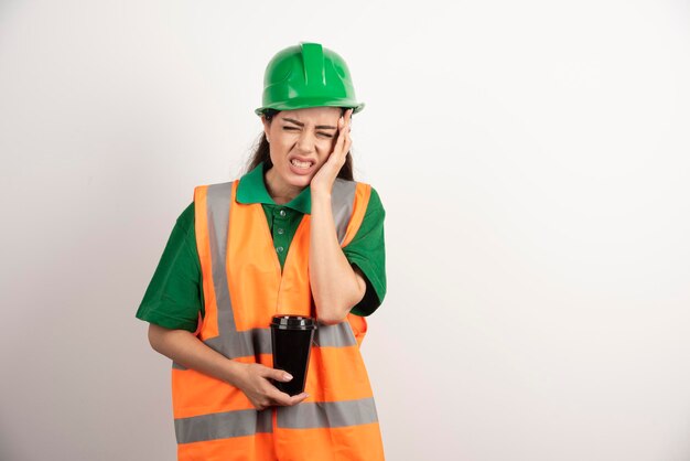 Vrouwelijke constructeur met kop die haar hoofd aanraakt. hoge kwaliteit foto