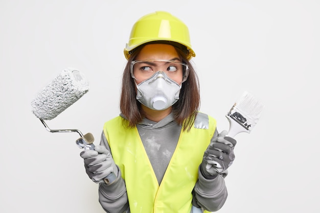 Vrouwelijke constructie-ingenieur in veiligheidsvest beschermende bril veiligheidshelm masker en handschoenen houdt apparatuur serieus opzij, klaar om het bouwgebied te betreden voor inspectie. Industrieel arbeider.