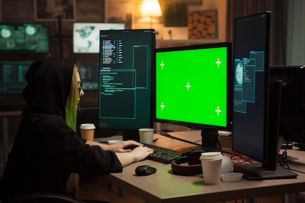 Vrouwelijke cybercrimineel typen op computer met groen scherm. bedrijfshacking.