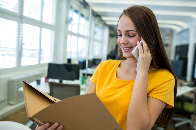 Vrouwelijke directeur met een bestand en praten op mobiele telefoon