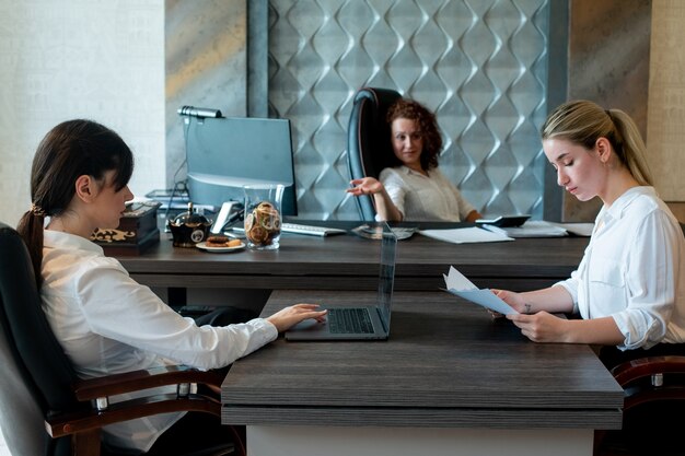 Vrouwelijke directeur van de jonge zakelijke dame zit aan een bureau en bespreekt de resultaten of de planning van werk tijdens een groepsbijeenkomst met collega's die samenwerken in kantoor