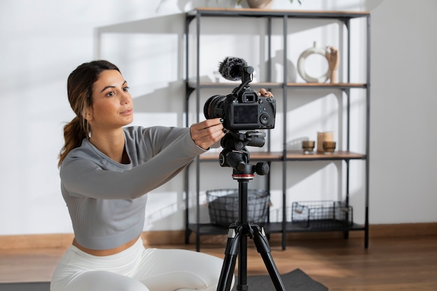 Gratis foto vrouwelijke fitnessinstructeur die thuis camera opzet om online les te geven