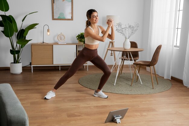 Vrouwelijke fitnessinstructeur die vanuit huis een online les geeft met behulp van een tablet