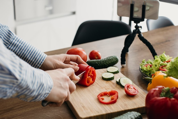 Vrouwelijke food blogger streaming met smartphone thuis tijdens het koken