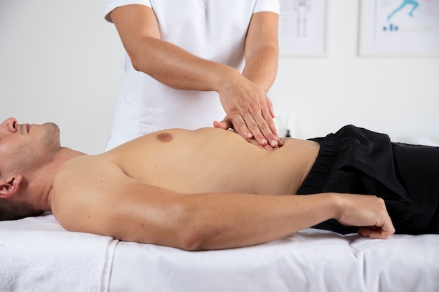 Vrouwelijke fysiotherapeut masseert mannelijke patiënt op kantoor
